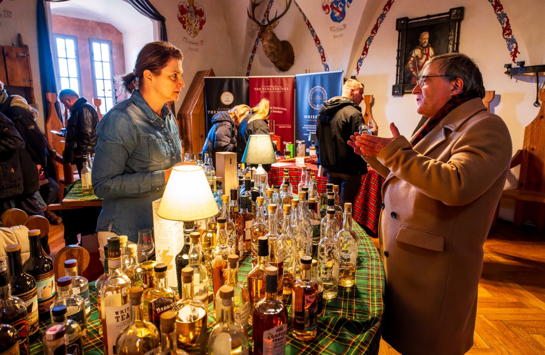 Besucher im Gespräch an einem Whiskystand im Schloss Trebsen